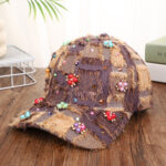 Blue-patchwork-denim-baseball-cap-featuring-distressed-frayed-edges-and-colorful-pearl-jewel-rhinestones-flower-cluster-embellishments-on-a-wooden-background-7