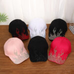 White-baseball-cap-featuring-a-shiny-crystal-rhinestone-flame-pattern-on-the-front-and-brim-placed-on-a-wooden-table-1