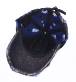 Wholesale-washed-black-denim-baseball-cap-with-custom-distressed-ripped-holes-revealing-a-bright-blue-underlayer-displayed-for-bulk-clothing-supplier-2
