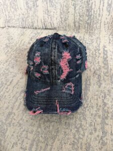 Wholesale-washed-black-denim-baseball-cap-with-custom-distressed-ripped-holes-revealing-a-bright-blue-underlayer-displayed-for-bulk-clothing-supplier-3-1